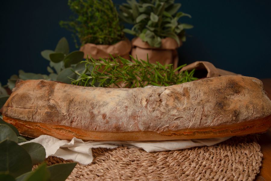 Golden loaf surrounded by fresh green herbs on a woven mat